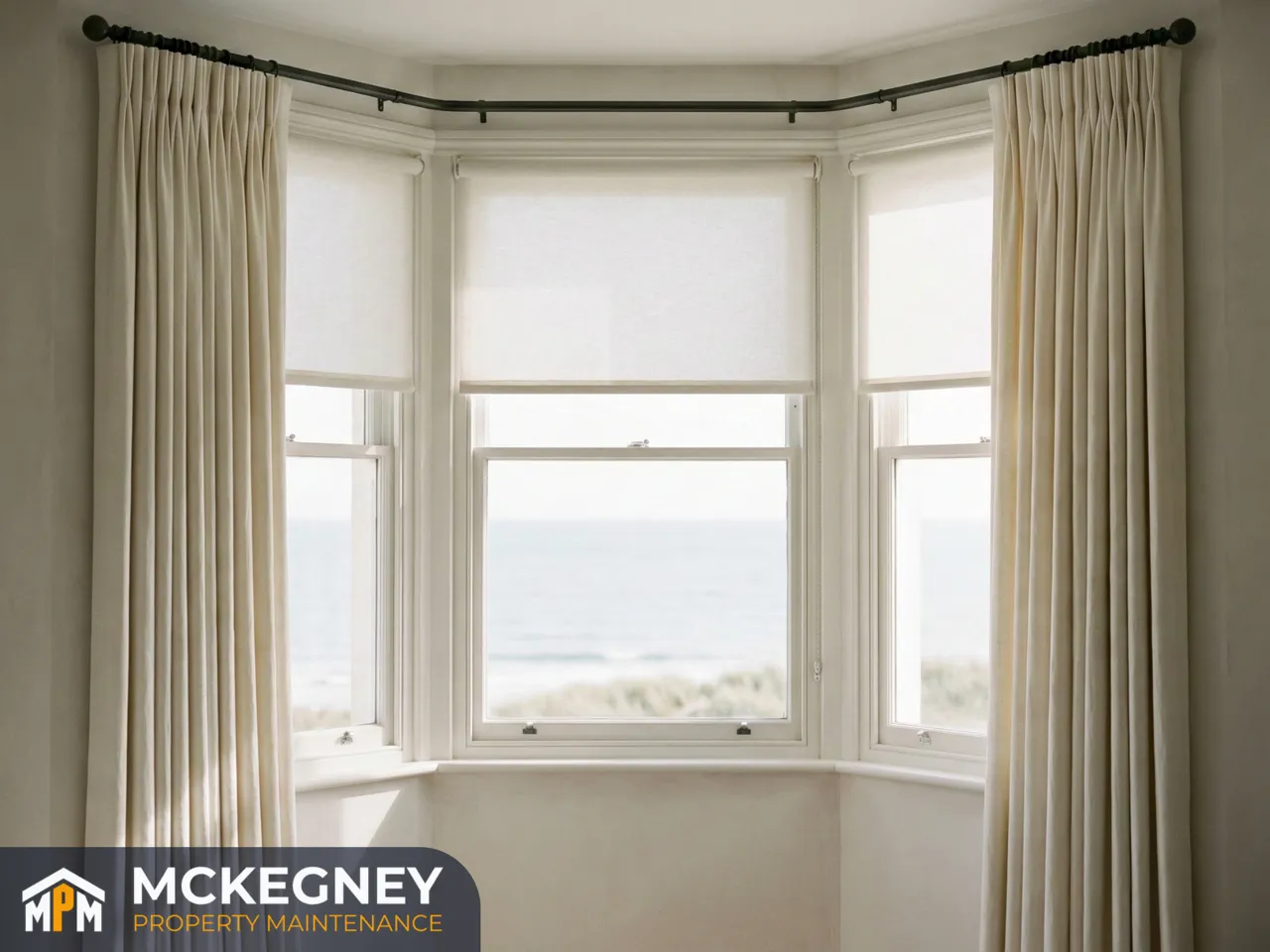 Bay window with evenly hung curtains on a straight pole and a neatly fitted roller blind — McKegney Property Maintenance.
