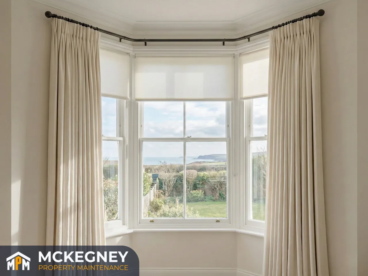 Bay window with neatly fitted roller blind and evenly hung curtains on a straight pole — McKegney Property Maintenance.
